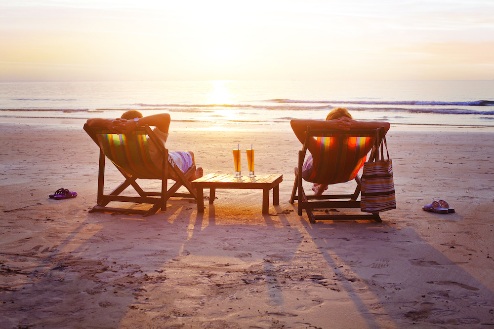 couple on beach relaxing in chairs watching sunset